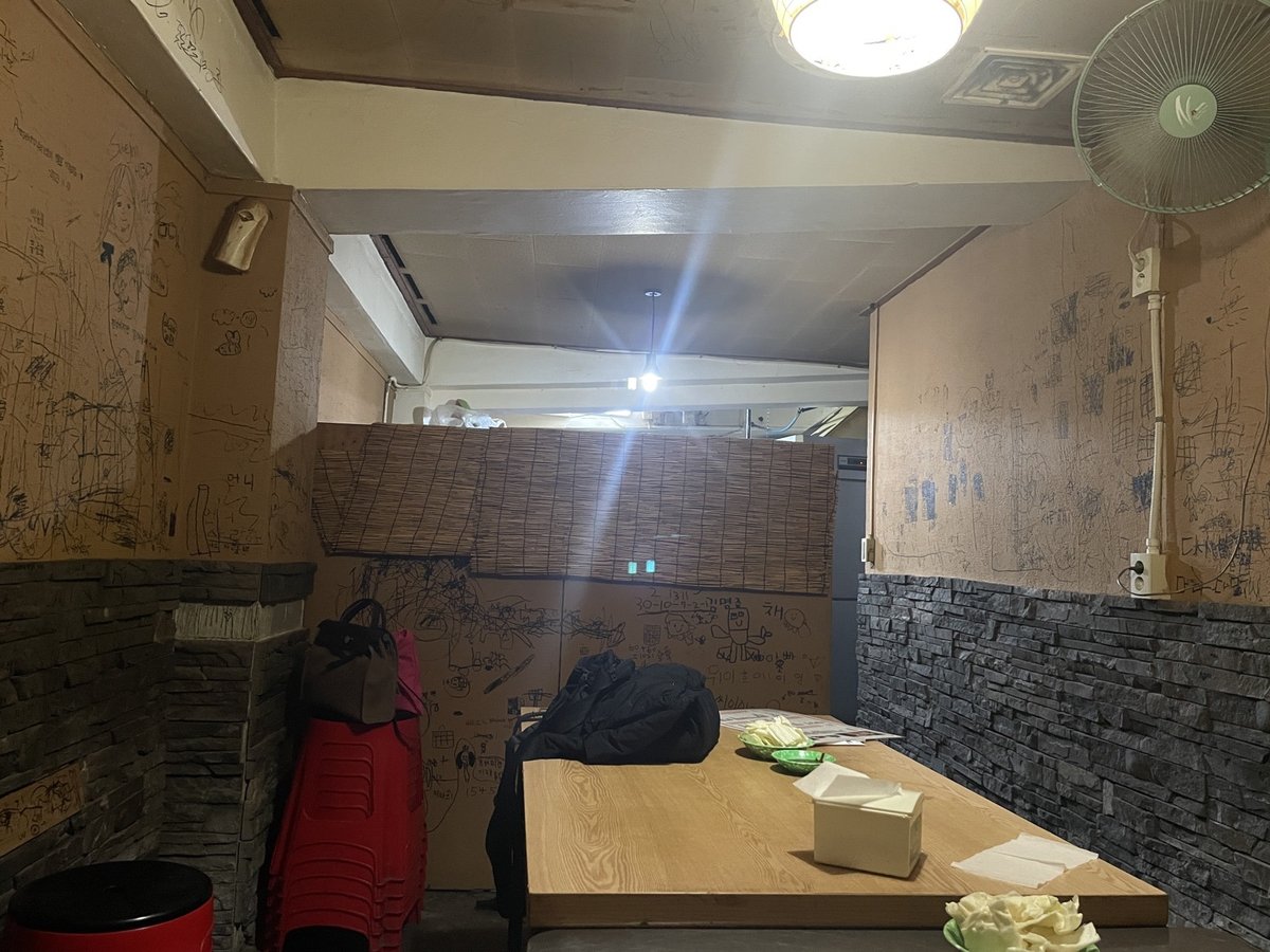낙서가 남은 벽과 오래 쓴 나무 탁자가 있는 지하 술집 내부