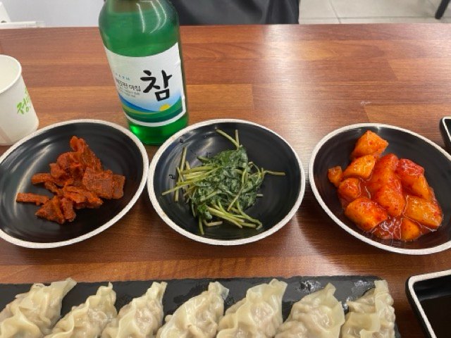 기본 반찬 세 가지와 만두, 소주 한 병이 놓인 상