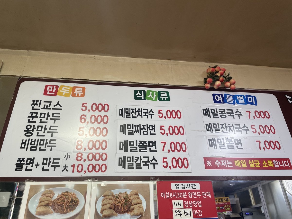 만두류와 식사류 가격이 적힌 벽 메뉴판과 영업시간 안내