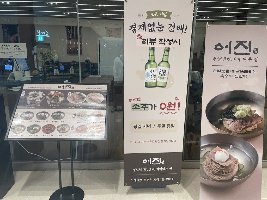 가게 입구 유리문 앞에 세워진 소주 0원 이벤트 배너